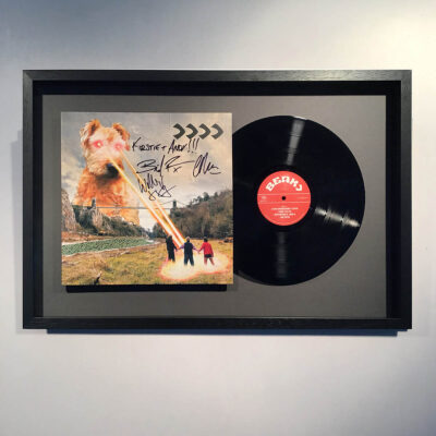A signed vinyl record and cover float mounted on grey mount board in a smooth black wooden frame