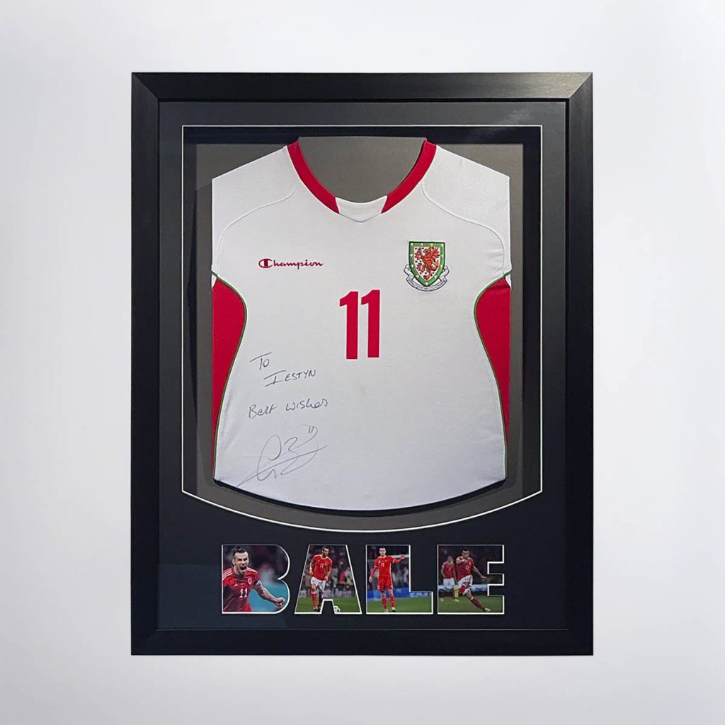 A stretched Christian Bale signed shirt. The name "Bale" is made from photos of him. It's on a dark grey mount in a black poly frame.