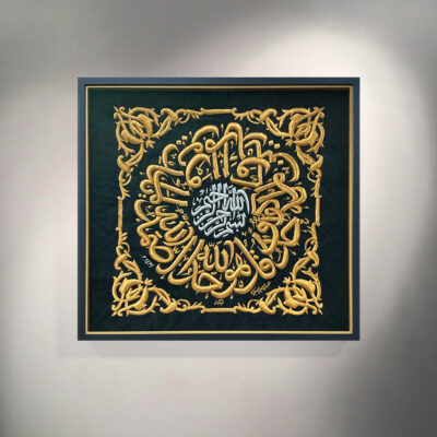 A large heavy black textile with gold coloured wire in a black and gold frame
